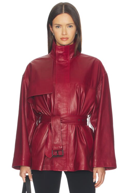 Cropped front studio portrait of a woman wearing a rich red smooth leather trench jacket with a high stand collar, chest storm flap, wide sleeves, and a cinched belted waist.
