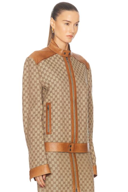 Side view of a structured brown patterned canvas motorcycle jacket highlighting the vertical zippered side pocket and fine stitching on the leather shoulder trim.