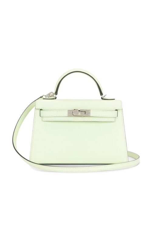 Front view of a mini trapezoidal pale mint green structured calfskin handbag featuring a structured top handle, silver-tone turnlock closure, and a thin matching leather shoulder strap on a plain white background.