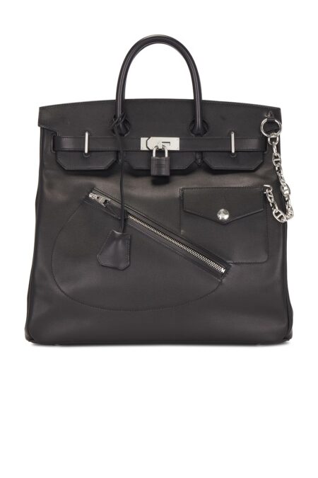 Front view of a limited edition black calfskin leather travel tote bag on a white background, highlighting a diagonal front zipper pocket, a snap flap pocket, a central leather-covered lock, and dual top handles.