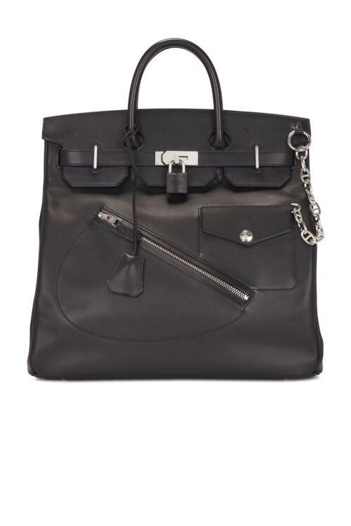 Front view of a limited edition black calfskin leather travel tote bag on a white background, highlighting a diagonal front zipper pocket, a snap flap pocket, a central leather-covered lock, and dual top handles.