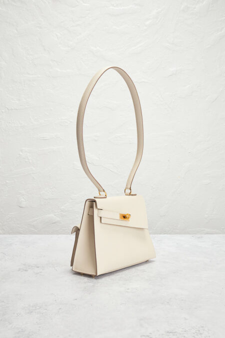 Close-up of cream leather handbag flap with gold turn-lock clasp
