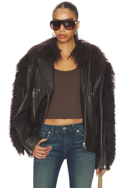 Cropped front view of a dark brown textured leather coat worn open over a brown crop top, featuring oversized dark faux fur trim on the collar and sleeves.