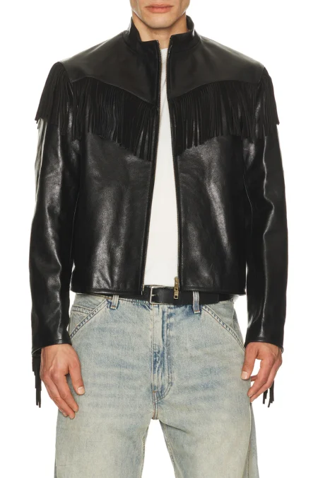 A close-up crop of a model wearing a black heavyweight cowhide leather jacket with a stand-up collar, front metal zipper, and distinct fringe paneling draping across the chest.