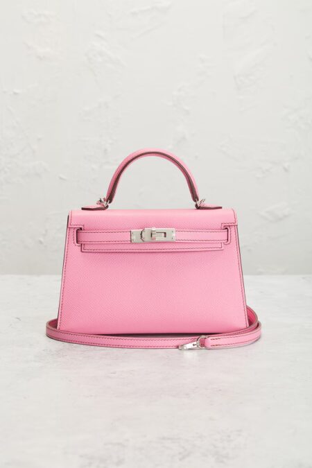 Luxury pink calfskin leather handbag photographed from the front with a detachable shoulder strap, structured top handle, and silver hardware against a neutral studio backdrop.