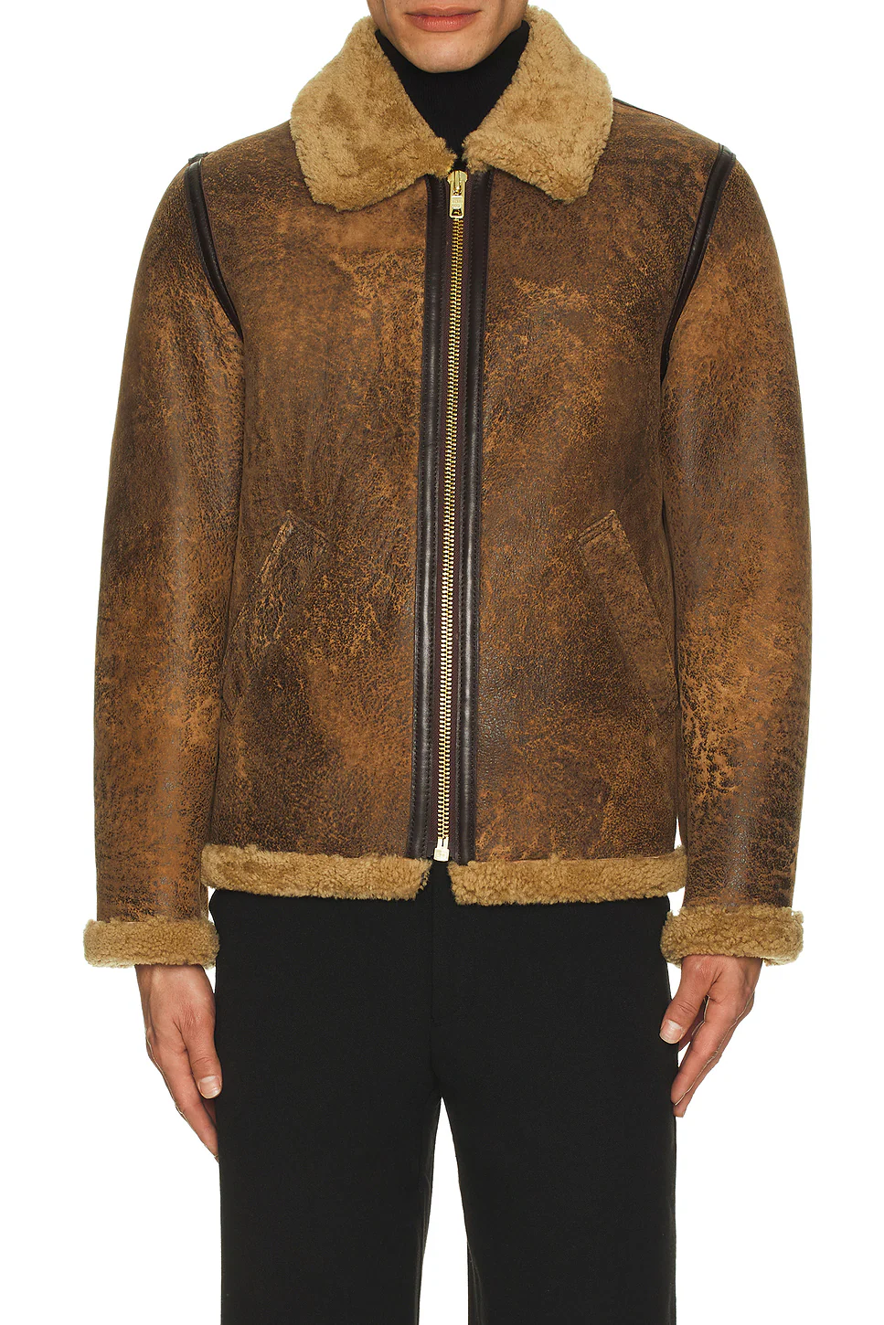Model wearing a fully zipped distressed brown leather flight jacket featuring a plush tan sheepskin shearling collar, waist trim, sleeve cuffs, and dark brown leather taped seams.