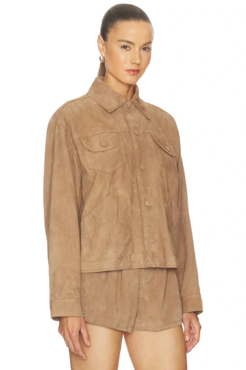 Three-quarter studio angle of a woman wearing a tan suede utility jacket fully fastened with tonal snap buttons, displaying structured chest flap pockets, drop shoulder seams, and sharp collar tailoring.