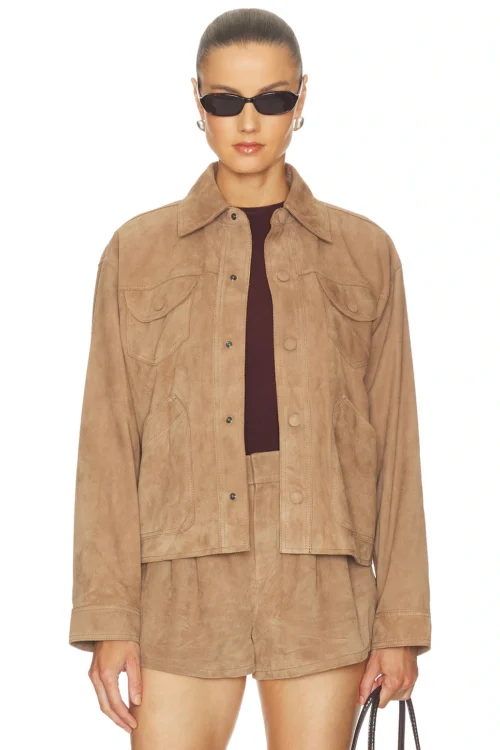 Cropped waist-up studio view of a woman wearing a tan lightweight suede utility jacket styled open over a dark burgundy knit top, showing a point collar, front snap placket, chest flap pockets, and side slant pockets.
