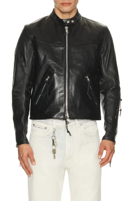 A close-up front view of a man wearing a premium black heavyweight leather jacket featuring a silver front zipper closure, two angled side zipper pockets, and a snap-button band collar styled with light denim.
