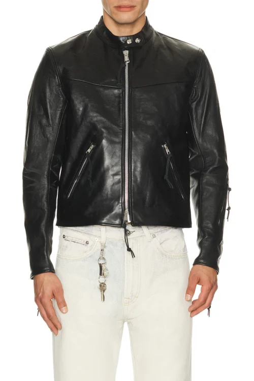 A close-up front view of a man wearing a premium black heavyweight leather jacket featuring a silver front zipper closure, two angled side zipper pockets, and a snap-button band collar styled with light denim.