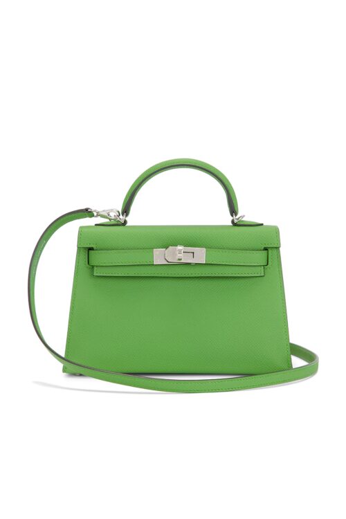 Front view of a vibrant green mini handbag made from textured Epsom leather featuring a single top handle, curved thin shoulder strap, silver-tone turnlock closure, and structured trapezoid body against a plain white background.
