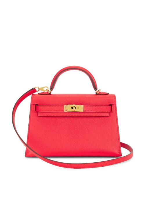 Front view of a vibrant pink structured mini handbag crafted from textured leather featuring a top handle, attached removable shoulder strap, classic sangles straps, and gold-tone turnlock hardware against a plain white background.